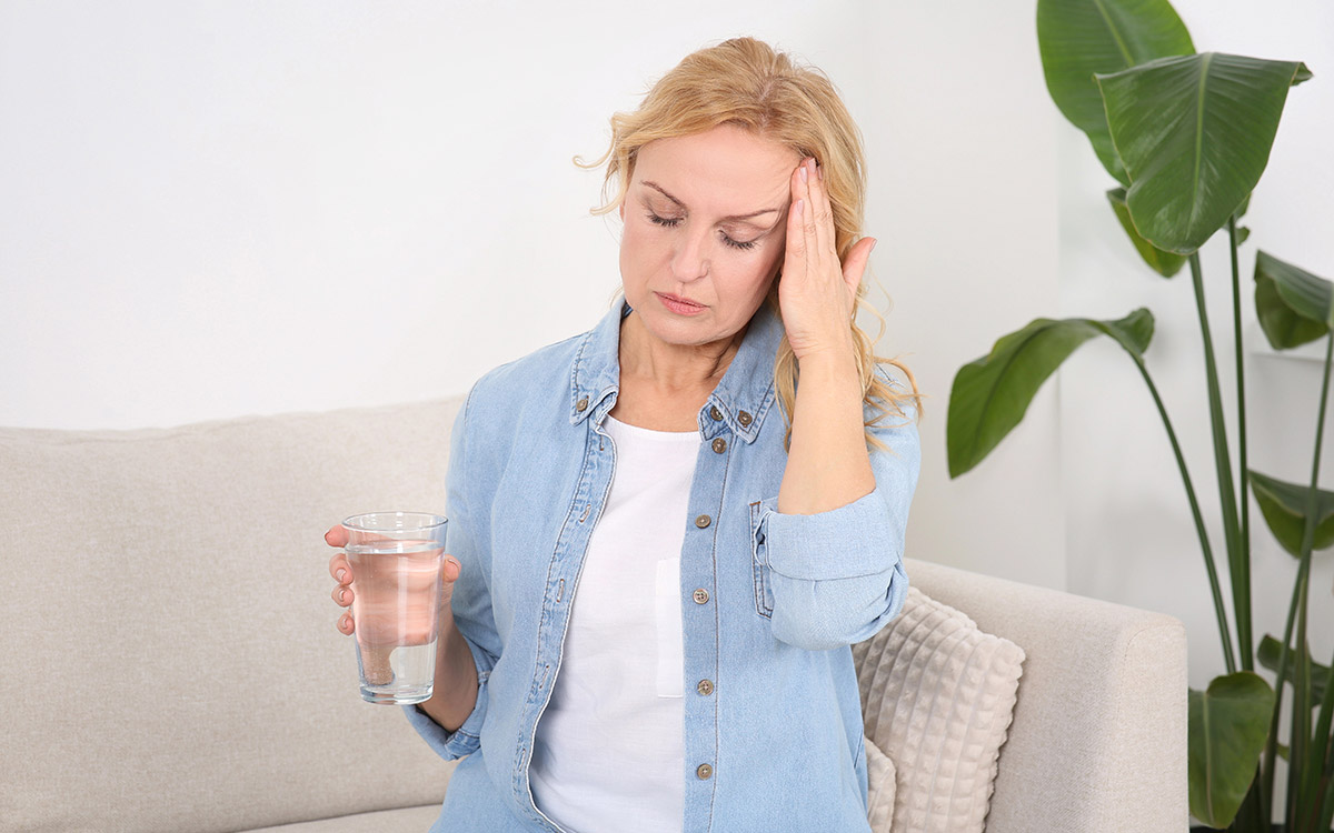 Woman with glass of water suffering from headache