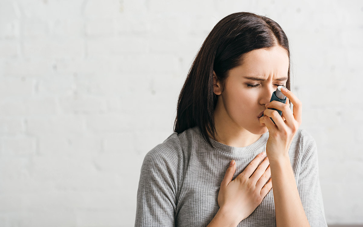 woman using asthmatic inhaler at home