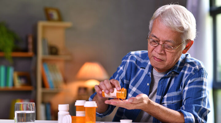 Asian senior man taking medicine at home