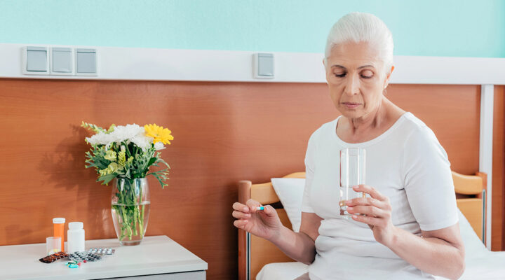 Senior woman taking medicine next to her bed