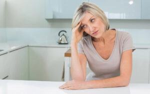 mature woman in her kitchen thinking