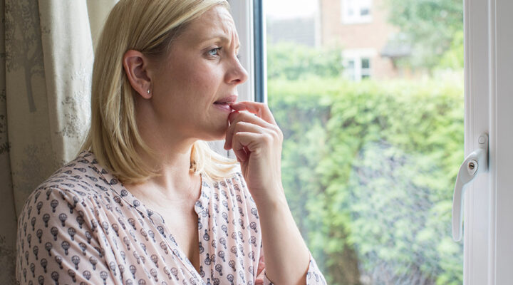 woman at home looking at the window worried