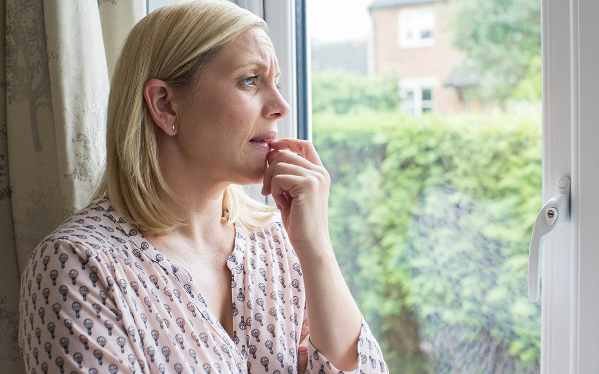 woman at home looking at the window worried
