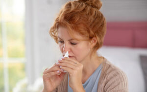 woman using a nasal spay at home