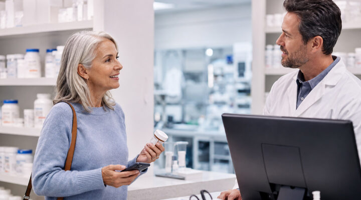 Older woman discussing a prescription transfer with a pharmacist at a modern compounding pharmacy counter